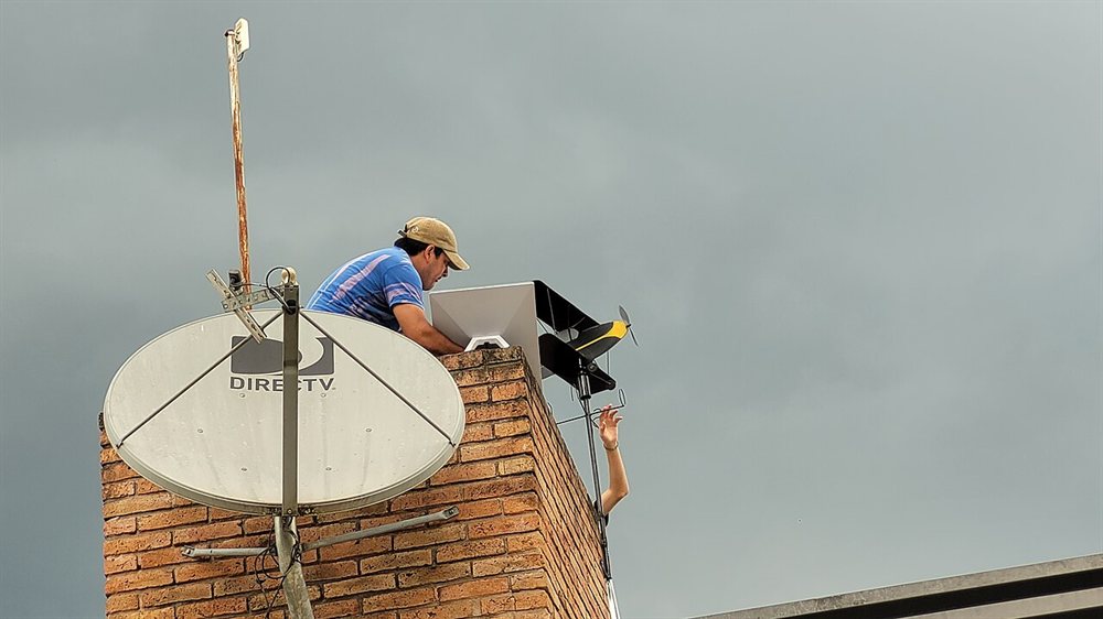 Technician mounting a Starlink dish during a rooftop installation